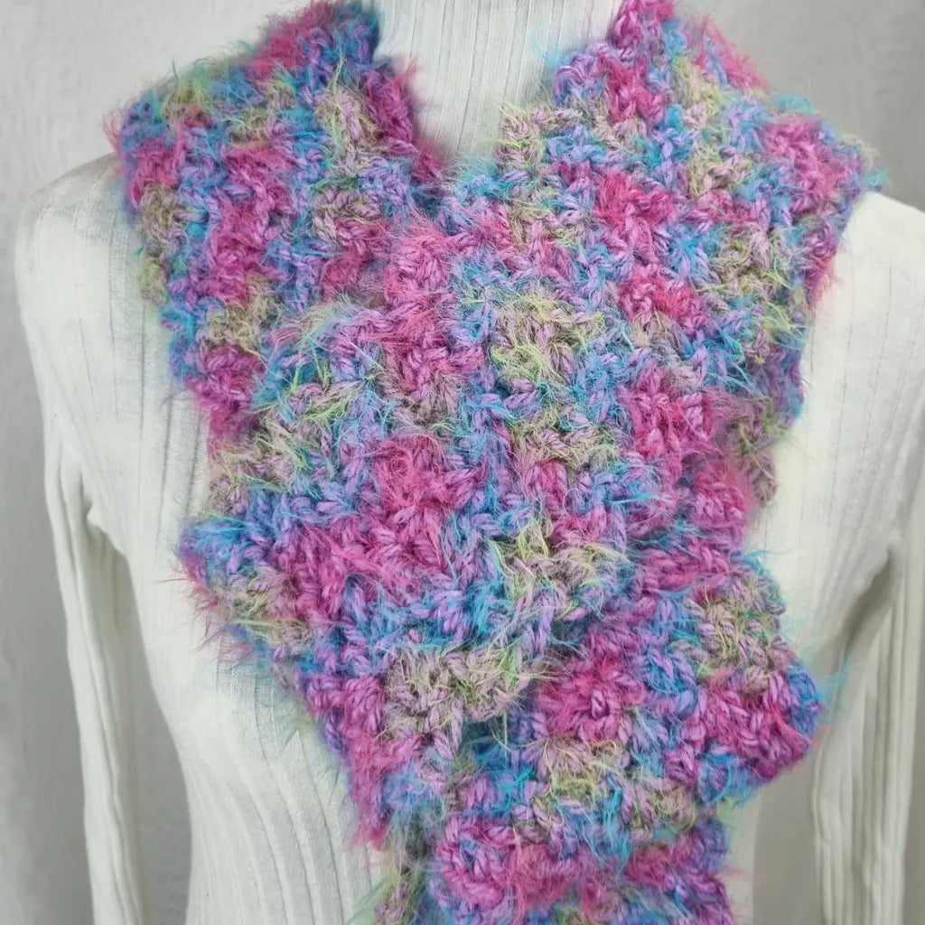 Multicolored knitted scarf on a mannequin against a plain background