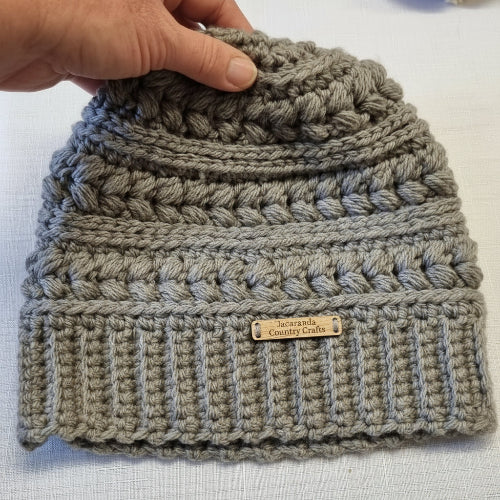 Gray knitted beanie with a brand label on a white background