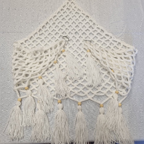 White macrame wall hanging with tassels on a light gray background